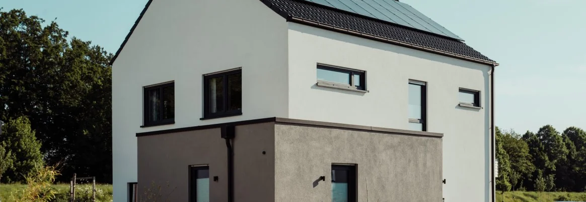 Modernes Haus mit Solaranlage und zweifarbiger Fassade.